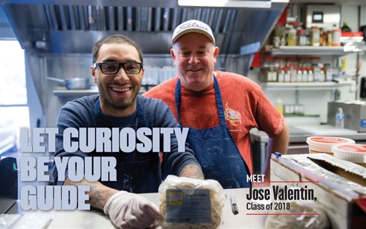 Young man smiling and holding ingredients in the foreground, with an older man smiling in the background and text in the foreground that says "let curiosity be your guide." 