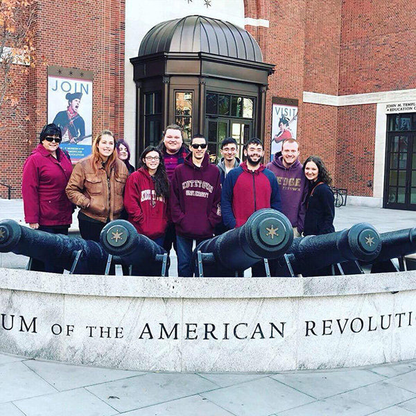Dr. Derr and students standing behind sign at Museum of the American Revolution