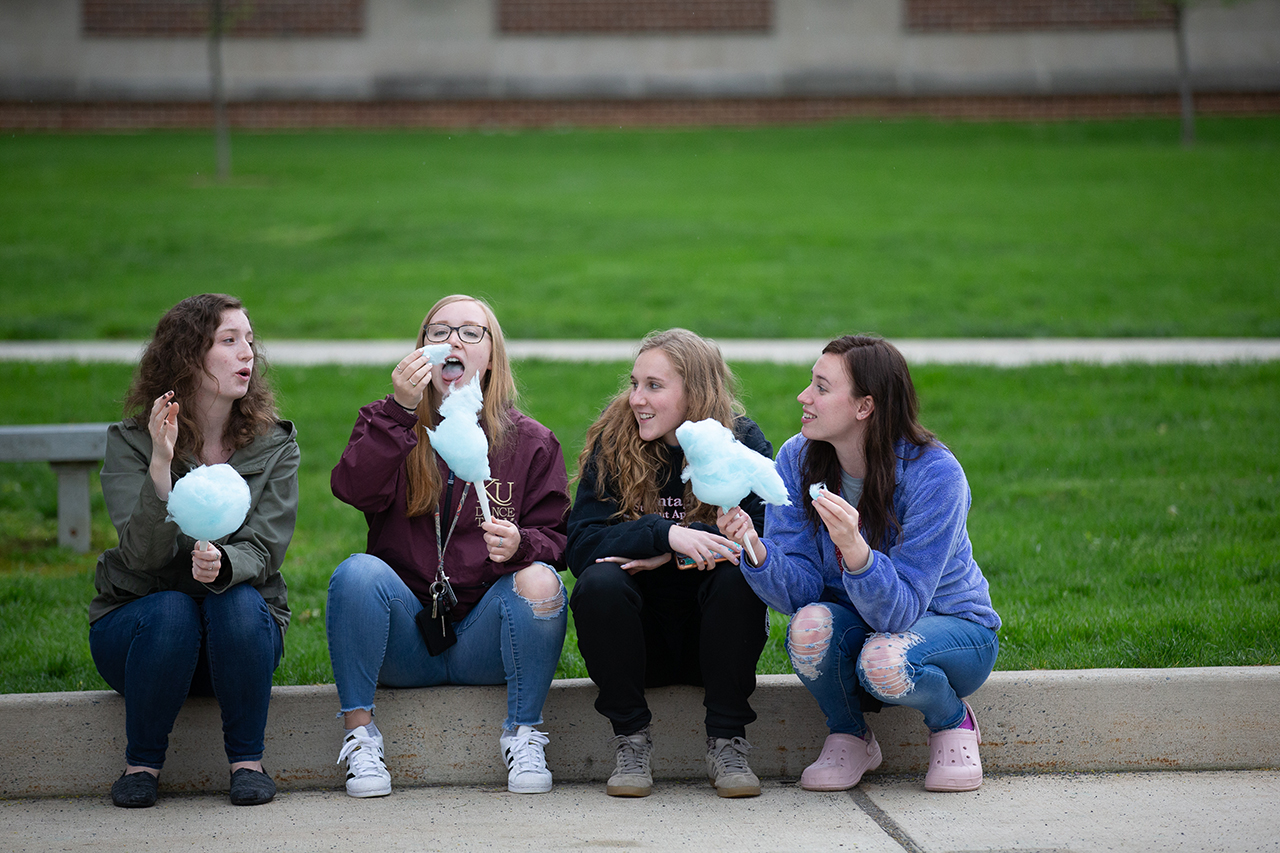 students sitting on a curb eating cotton candy