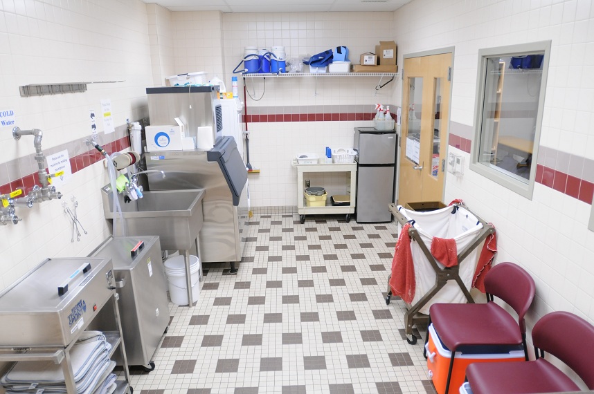Wide shot of the hydrotherapy room, with baths, steam machines, chairs and various medical equipment lining the walls