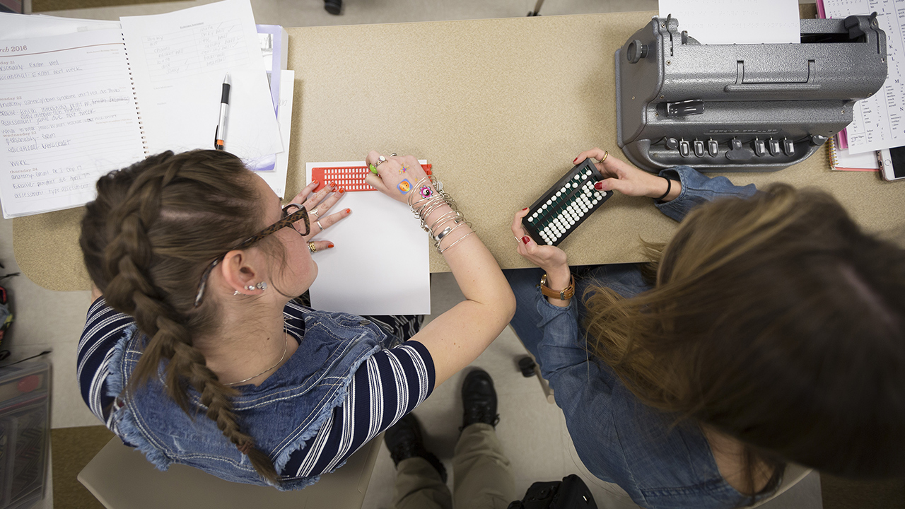 two students working together to learn about braille tools hands-on