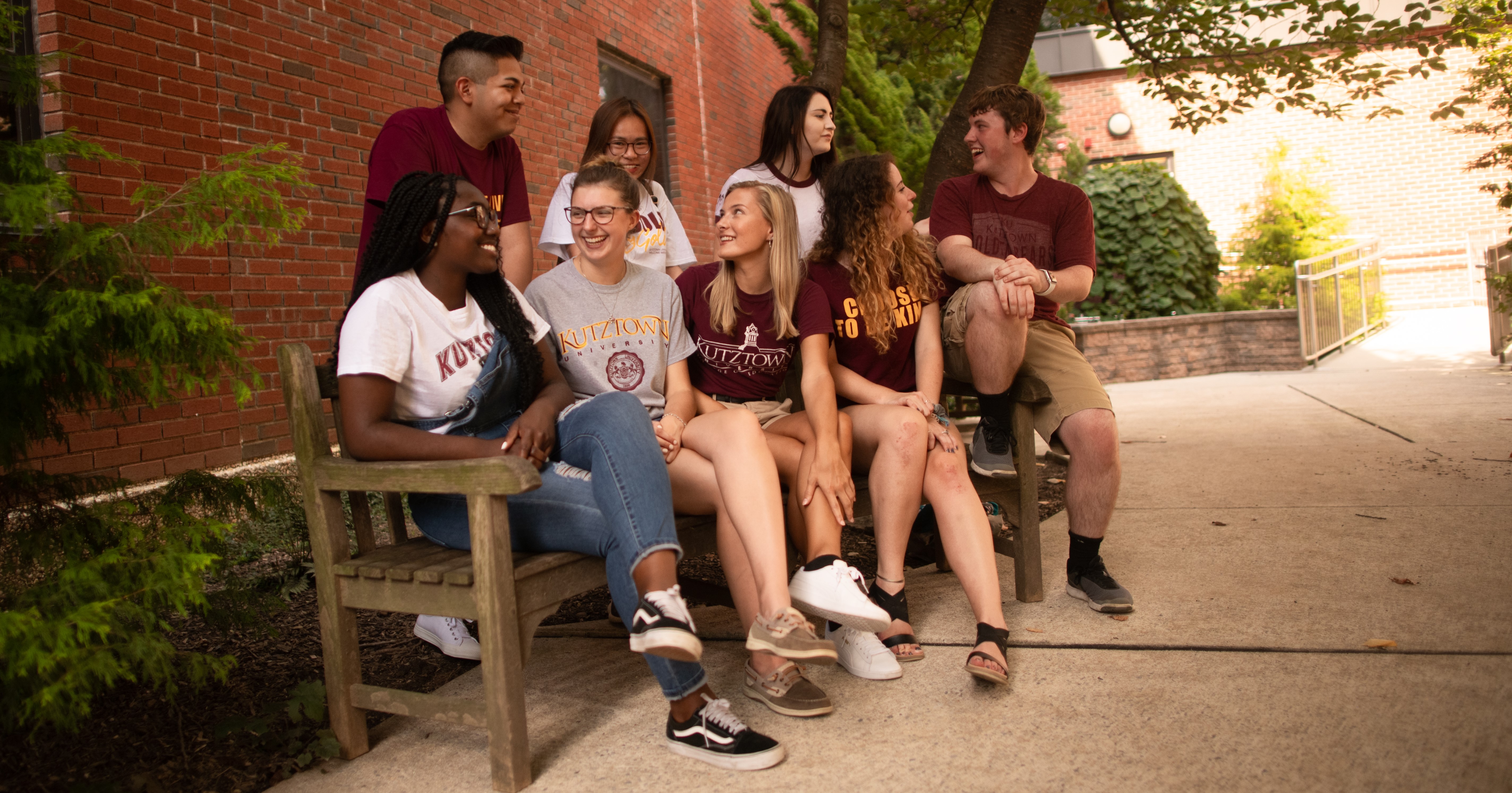 Group of students sitting on a bench outside and laughing 