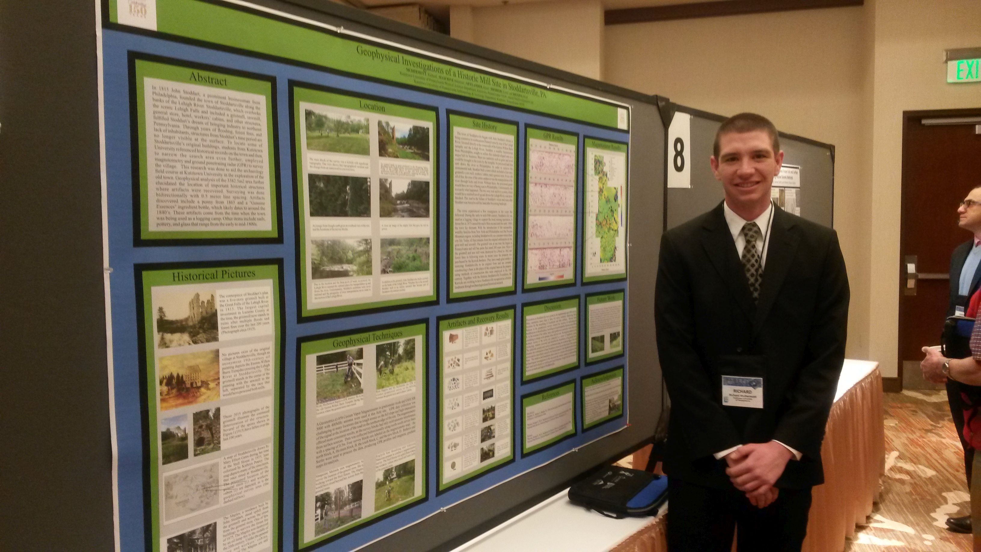 Male student standing beside his presentation on "geophysical investigations of a historic mill site in Stoddartsville, PA."