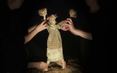 Three pairs of hands moving a female scarecrow puppet 