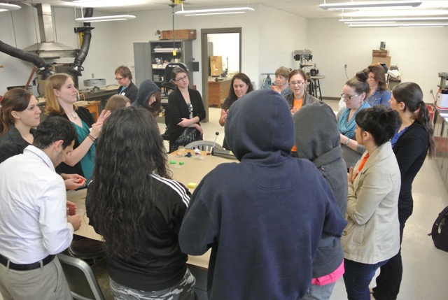 Group of art educators standing around a craft table and talking