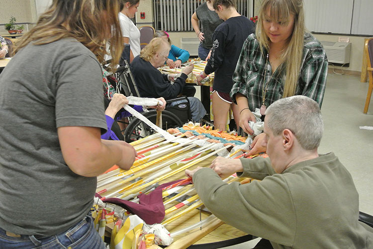 Art educators instruct elderly participants at craft tables 