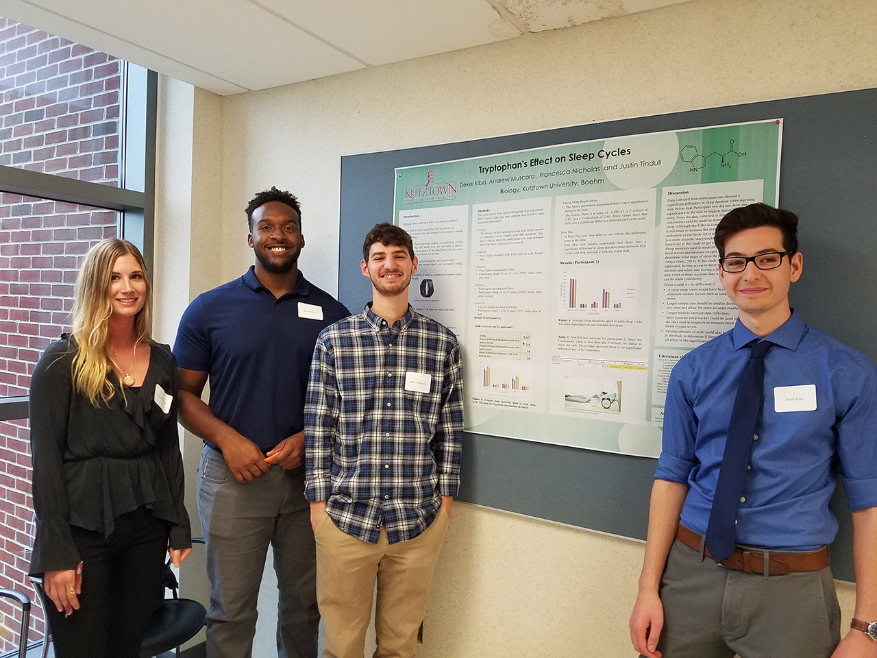 Four students standing in front of a poster on "tryptophan's effect on sleep cycles." 
