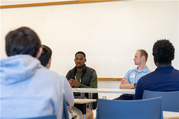 panelist sitting and networking with students in a classroom