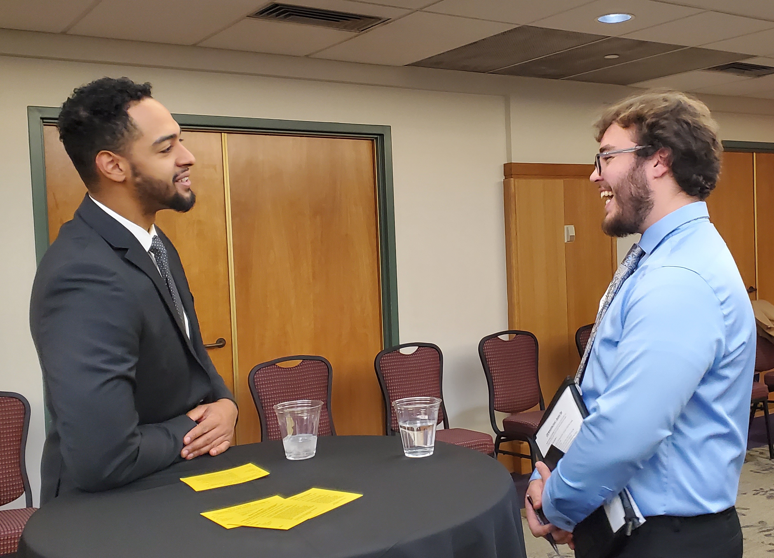 Student and recruiter smiling and talking to each other across a small circular table 