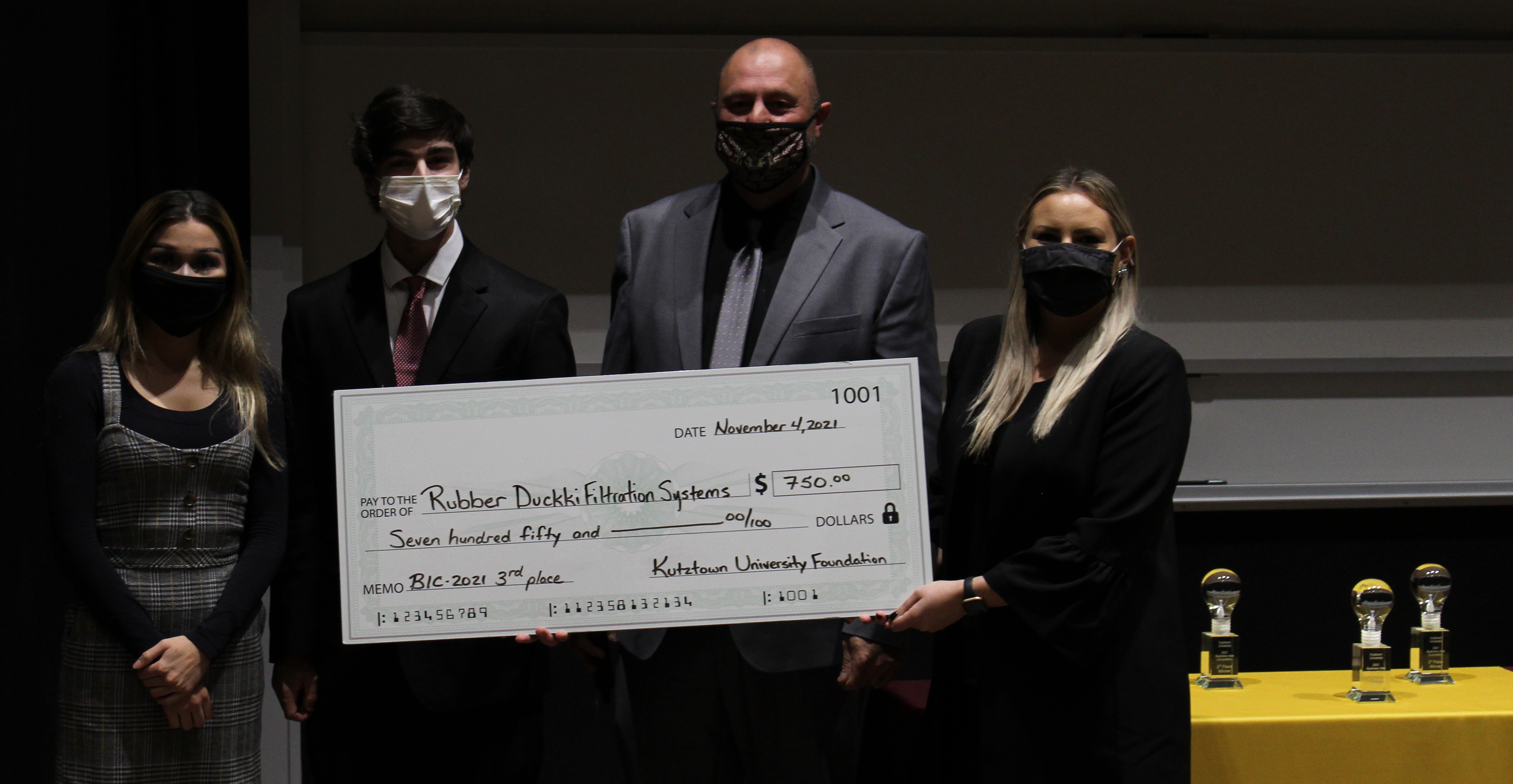 Matthew Sodano, third place winner, holding up a large check for $750 with the awarding judges.
