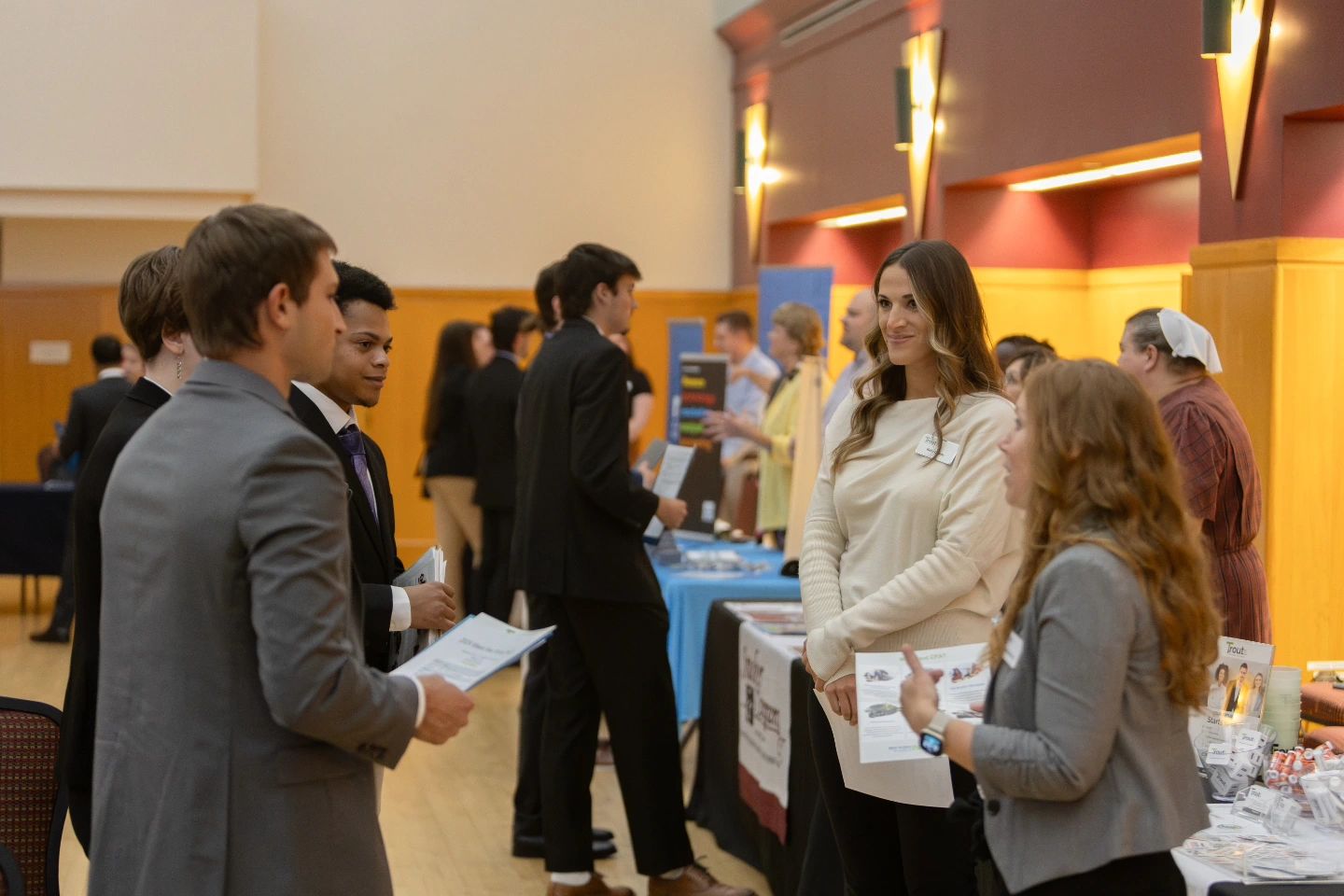 Students in professional attire speak with recruiters at information tables during a Meet the Firms event inside the McFarland Student Union building.