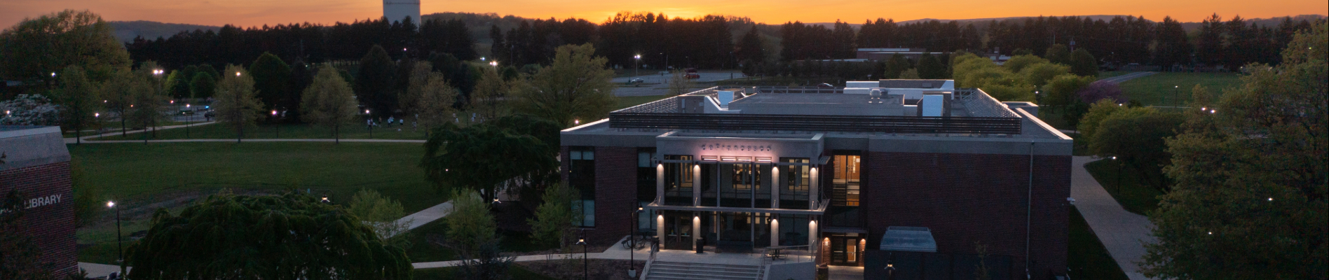 Kutztown University's campus with autumn leaves and students walking along the paths in the foreground.