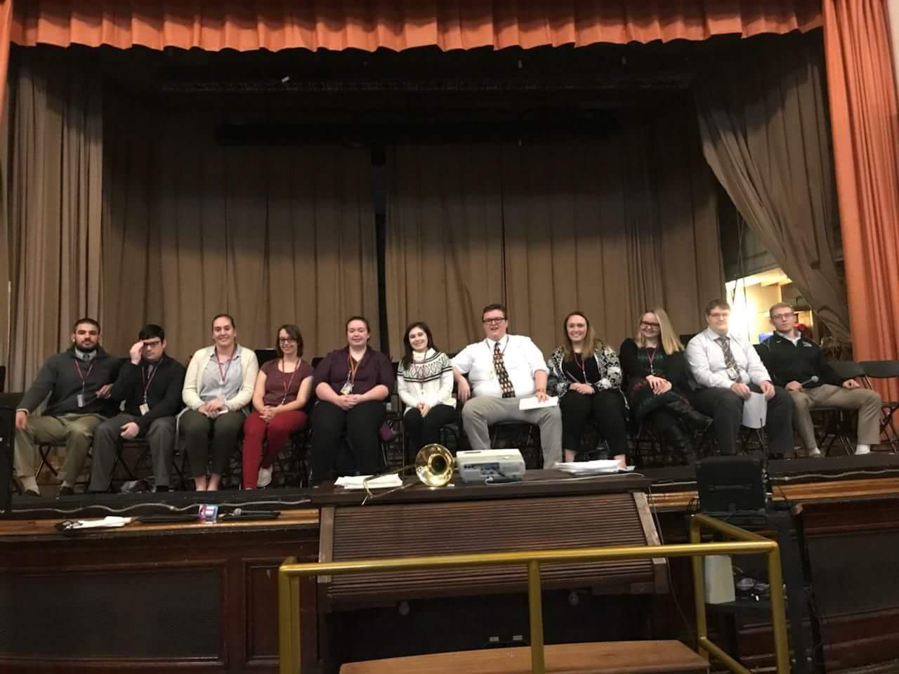 Student teachers sitting in a row on the auditorium stage of Reading Middle School