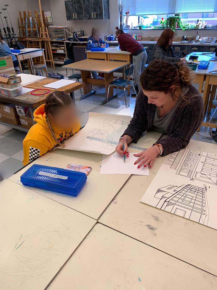 Student teacher Kelsey Meyers tutoring another student on architectural designs