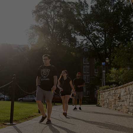 Students walking down a sidewalk outside on a sunny day