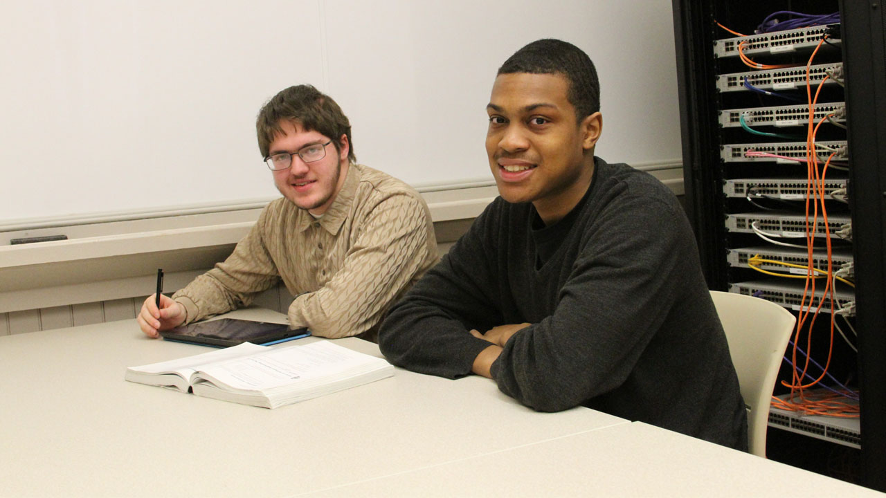 Two students doing homework in the computer lab.
