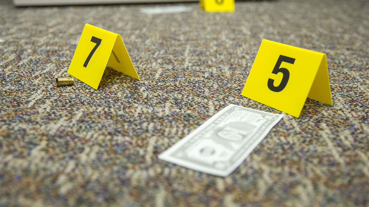 Crime scene scenario showing evidence markers no. 7, a bullet shell and no. 5, a ten dollar bill.