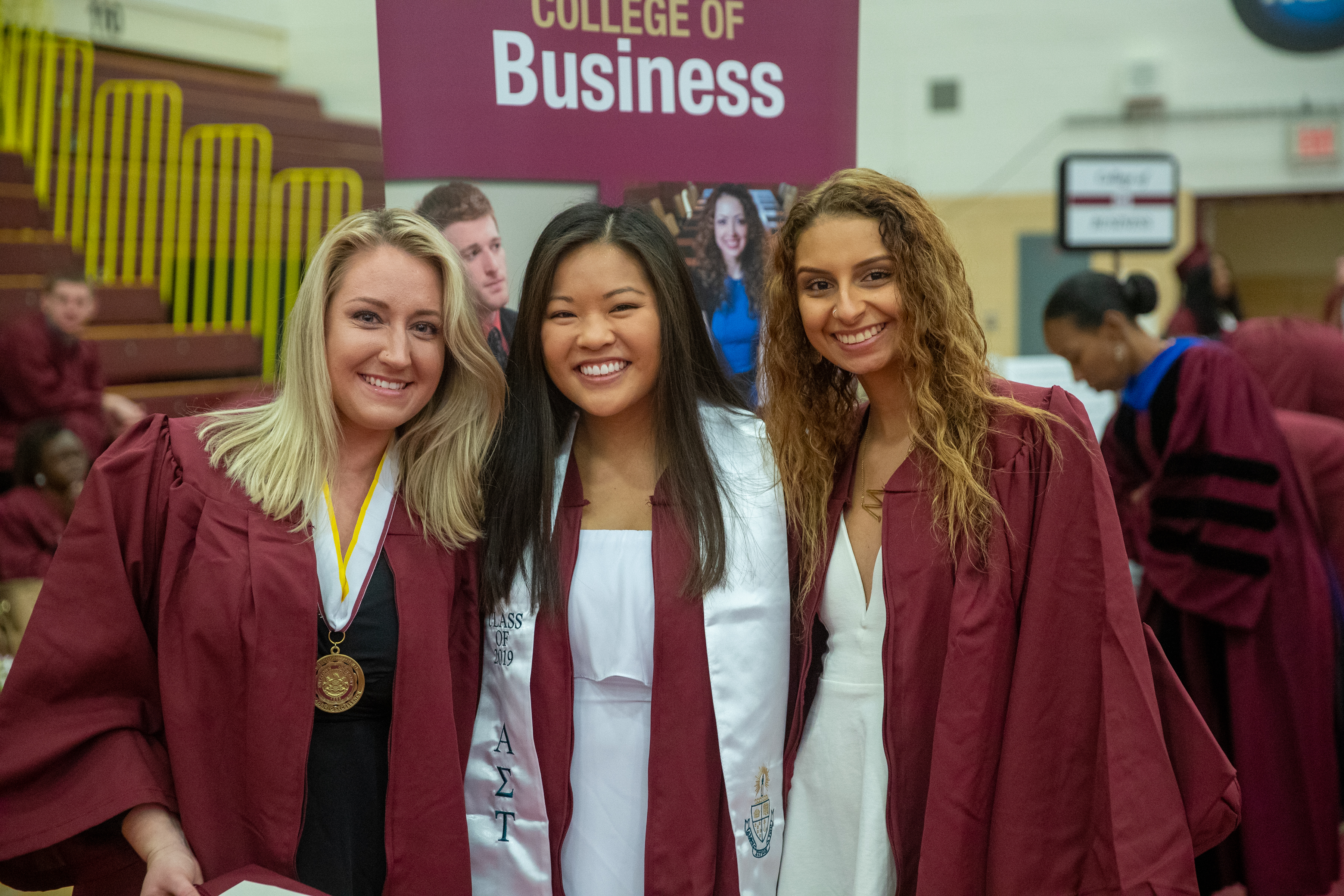 3 female students in graduation regalia smiling