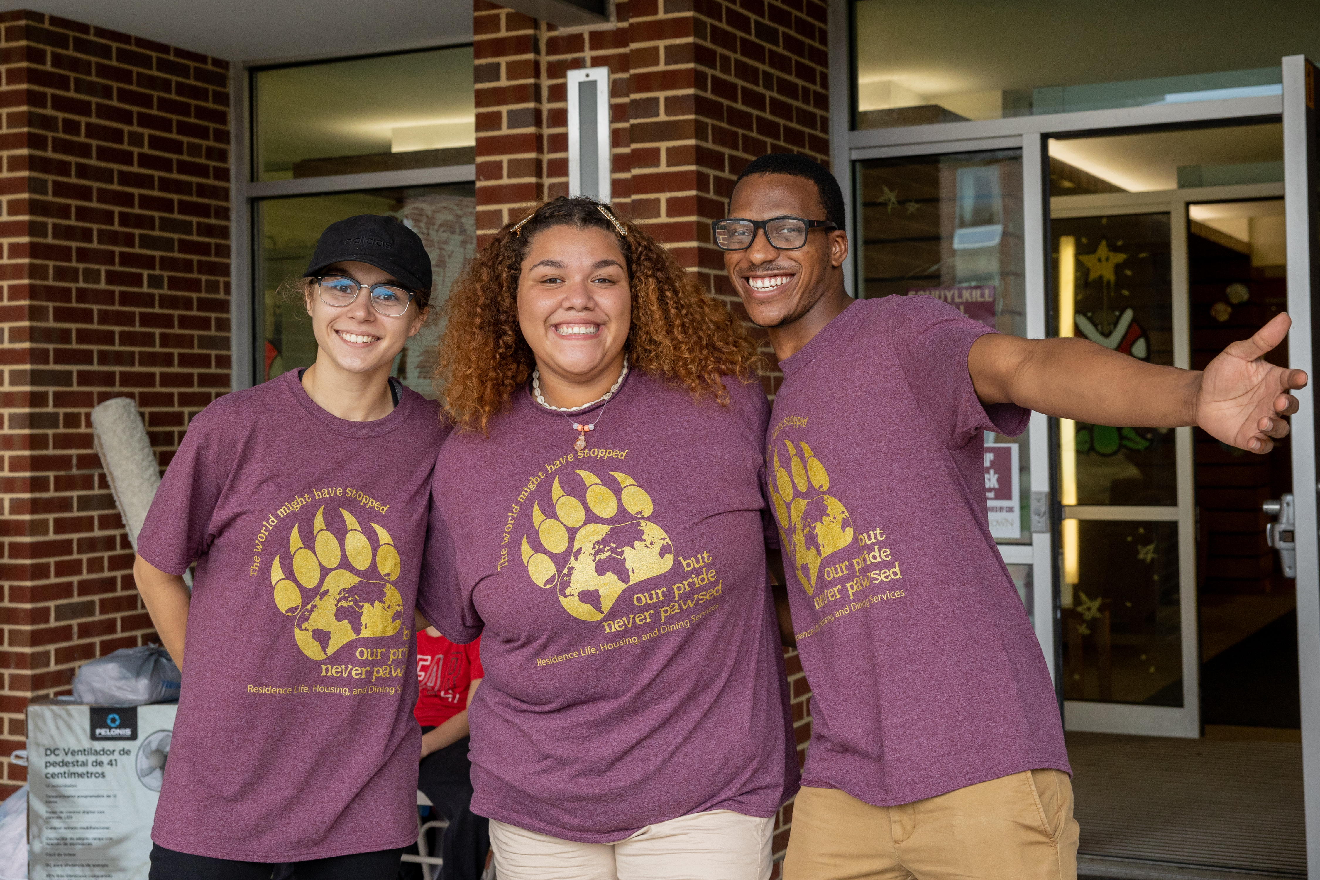 3 diverse students wearing KU maroon bear claw shirts and smiling