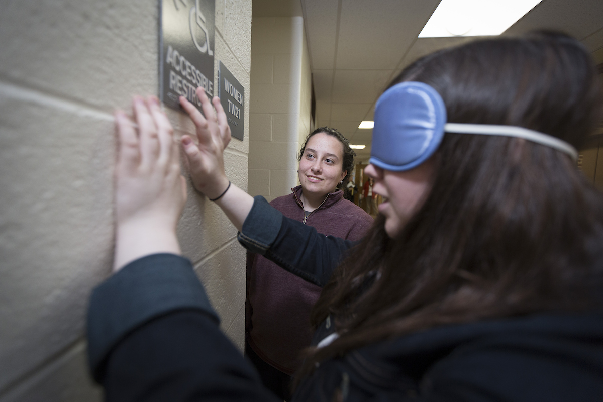 Student in the Visual Impaired program reading braille restroom sign