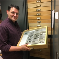 Dr. Setliff in front of his insect cabinet holding a single tray