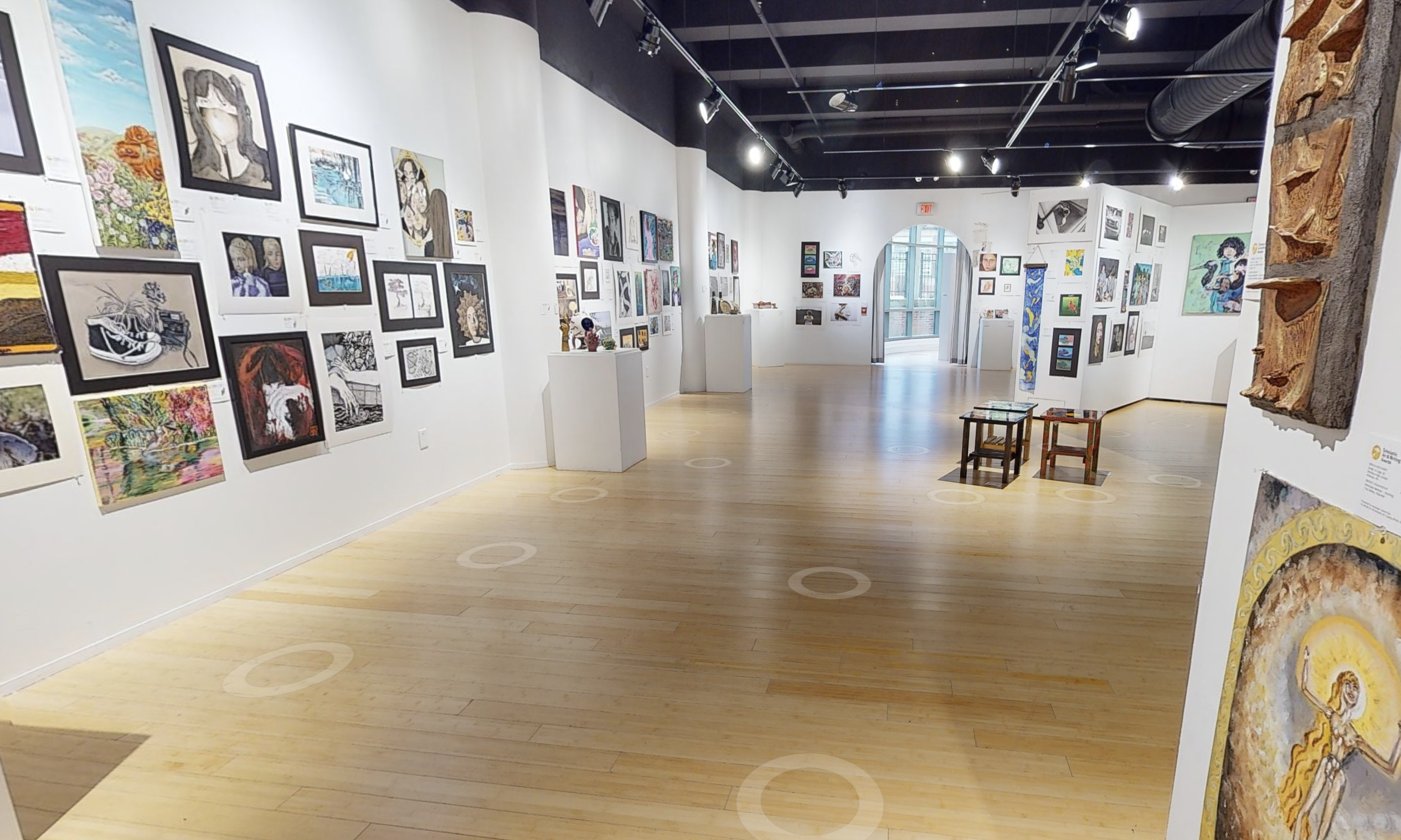 Wide shot of several gallery walls covered in paintings 