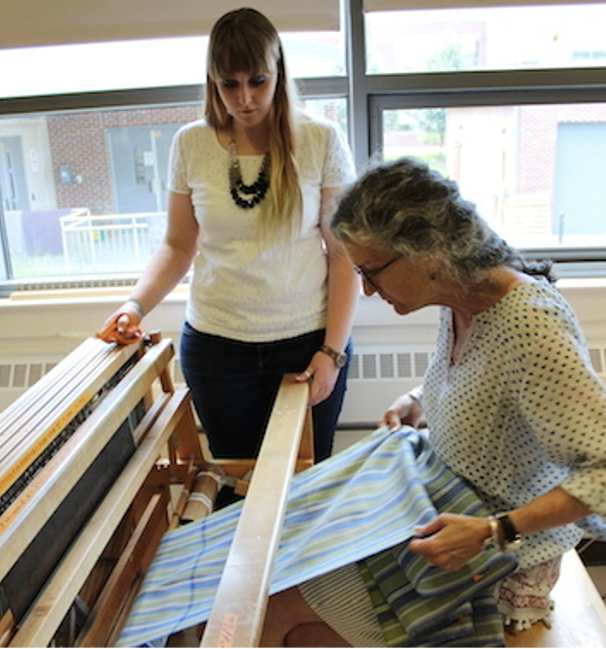 Female instructor and female student measuring out a length of striped fabric