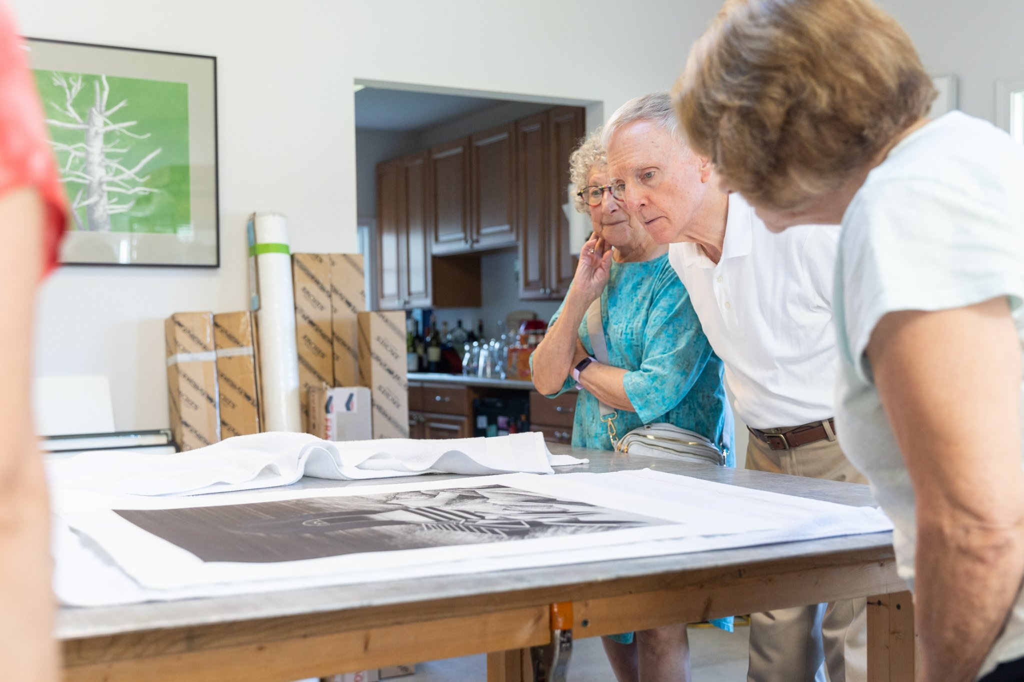 KU senior community members looking down at an etching example on a large table