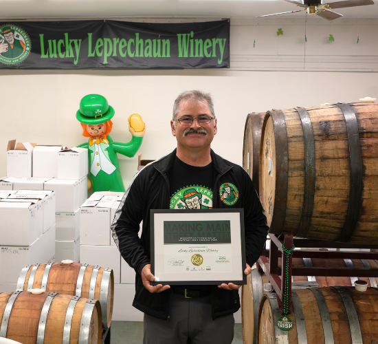 Man holding award in front of Lucky Leprechaun Winery sign
