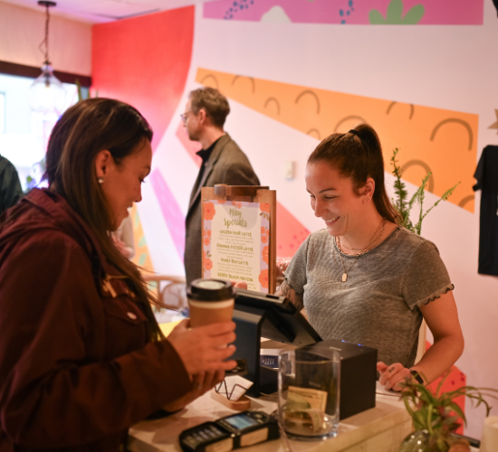 Coffee shop owner at register with customer