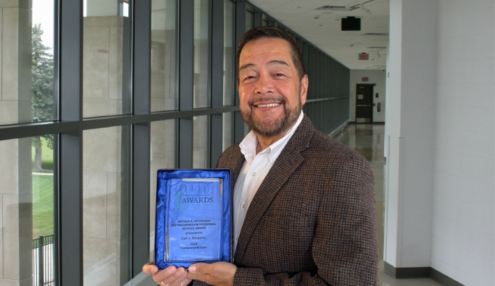 Dr. Carl Sheperis holding an award