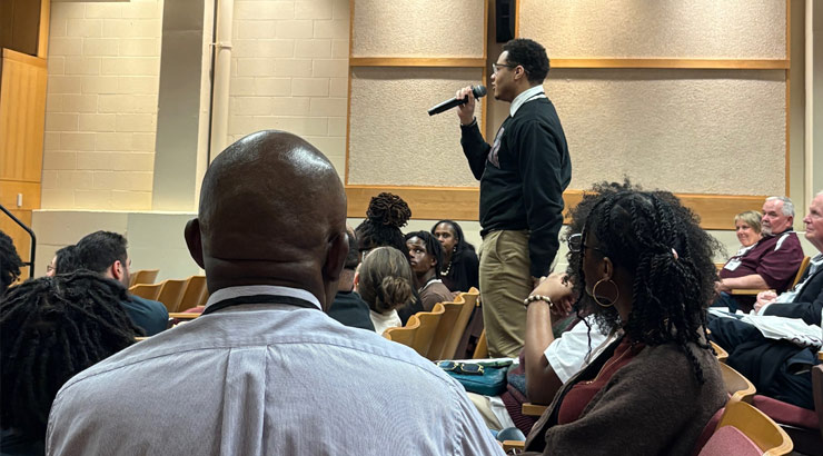 male student holding a microphone with audience members at an FDI event.