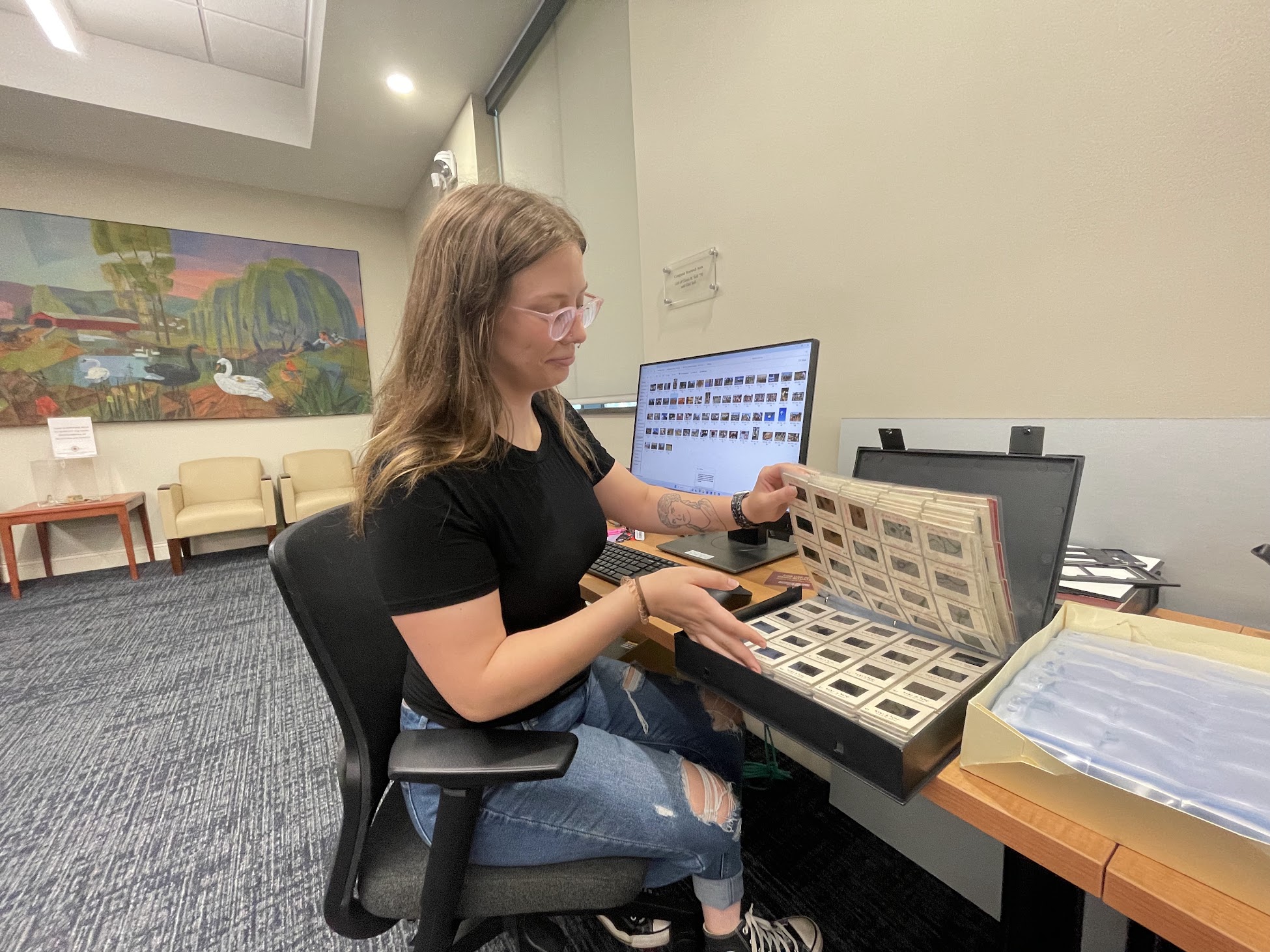 KU BEARS student working in Heritage Center, cataloging photograph slides.