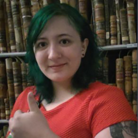 Samantha Miller giving a thumbs up in front of a library bookshelf 