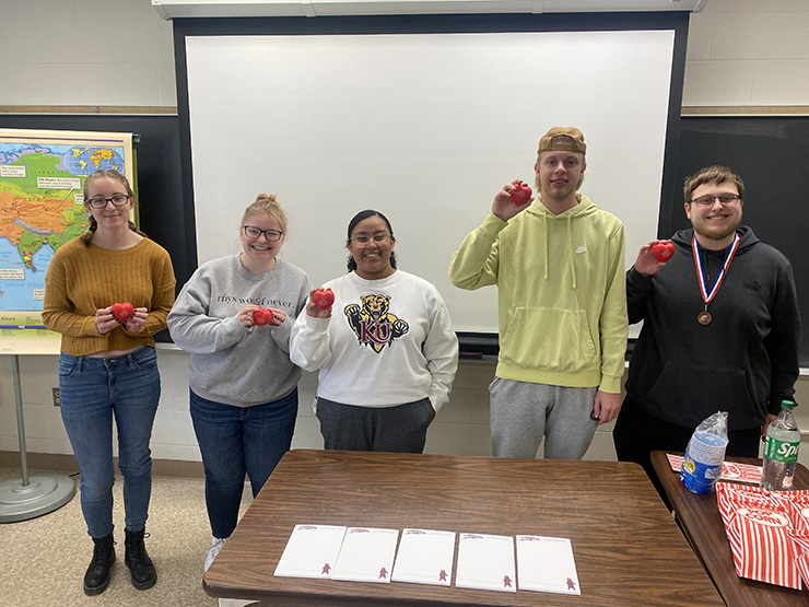 History club officers standing and holding heart stress balls
