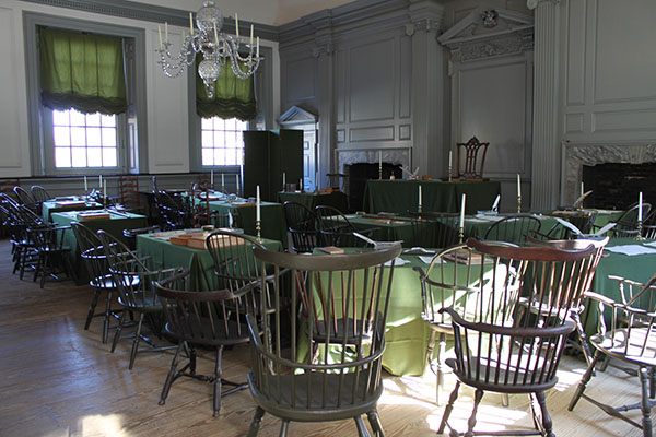 Interior of Constitution Hall, decorated with round tables covered in green cloth and antique-style chairs