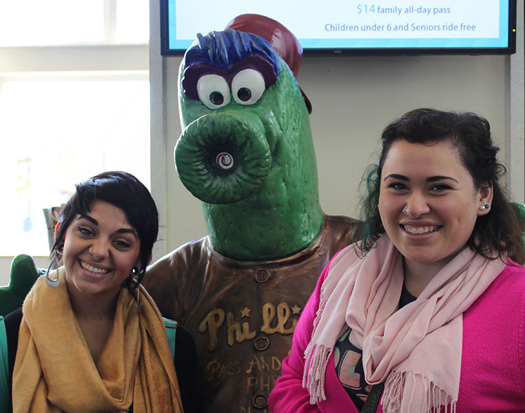 Two students posing with a statue of the Phillies fanatic mascot