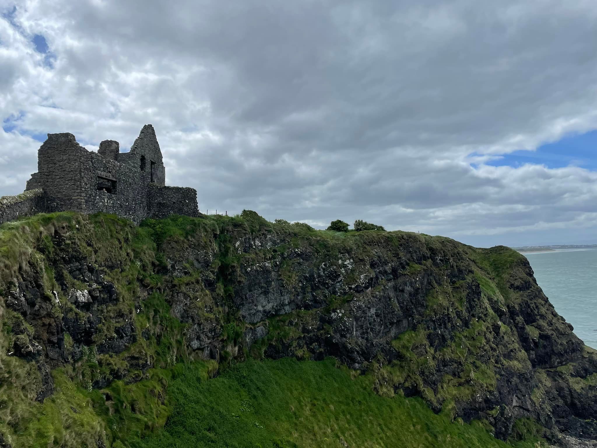Distant shot of a large, abandoned stone castle on a high cliff during a stormy day