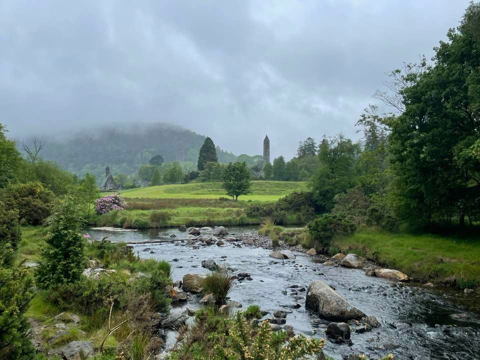 Distance shot of a rushing stream with mountains and pine trees in the background 