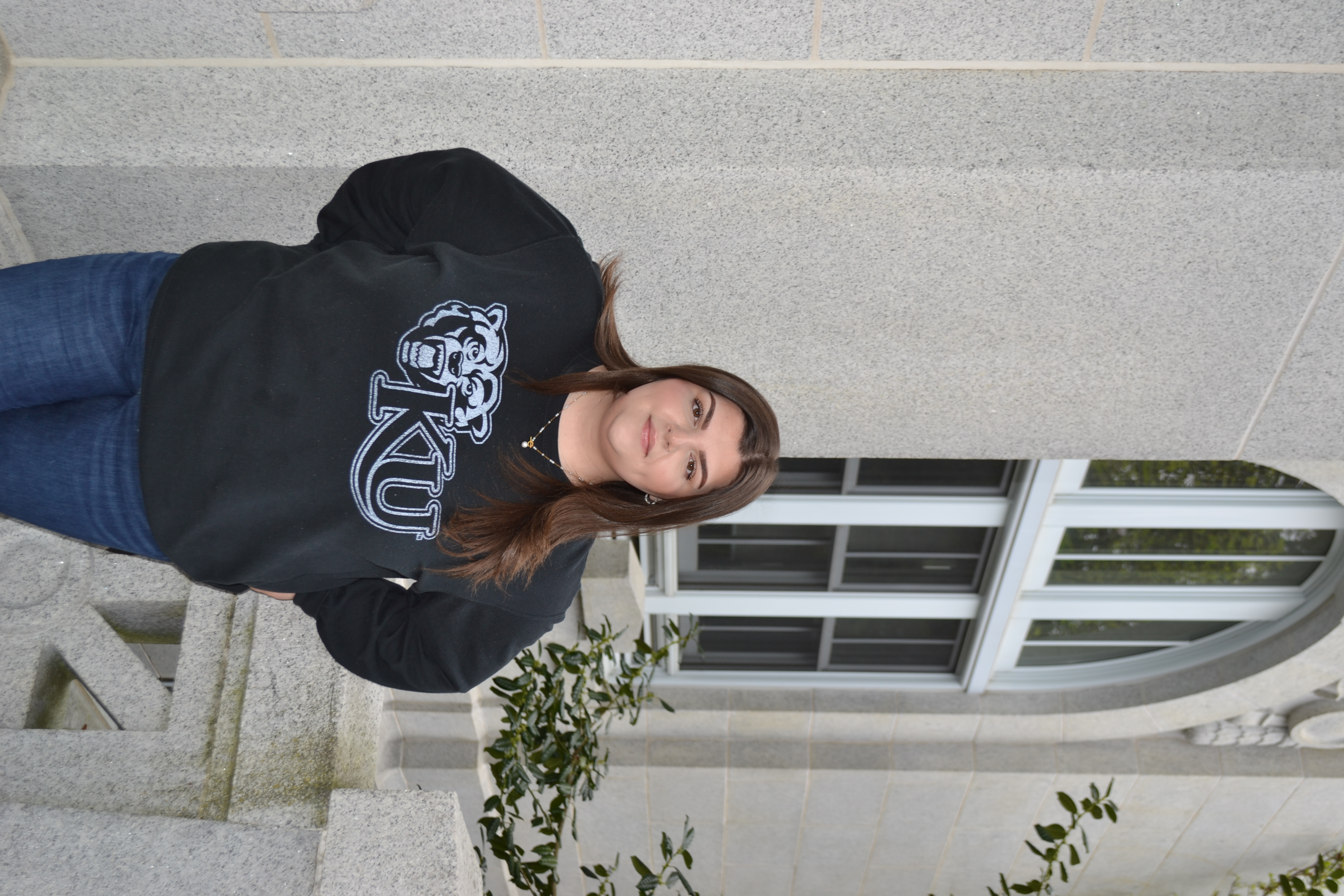 Transfer student Tabitha standing outside the Graduate Center wearing a black KU crew neck 