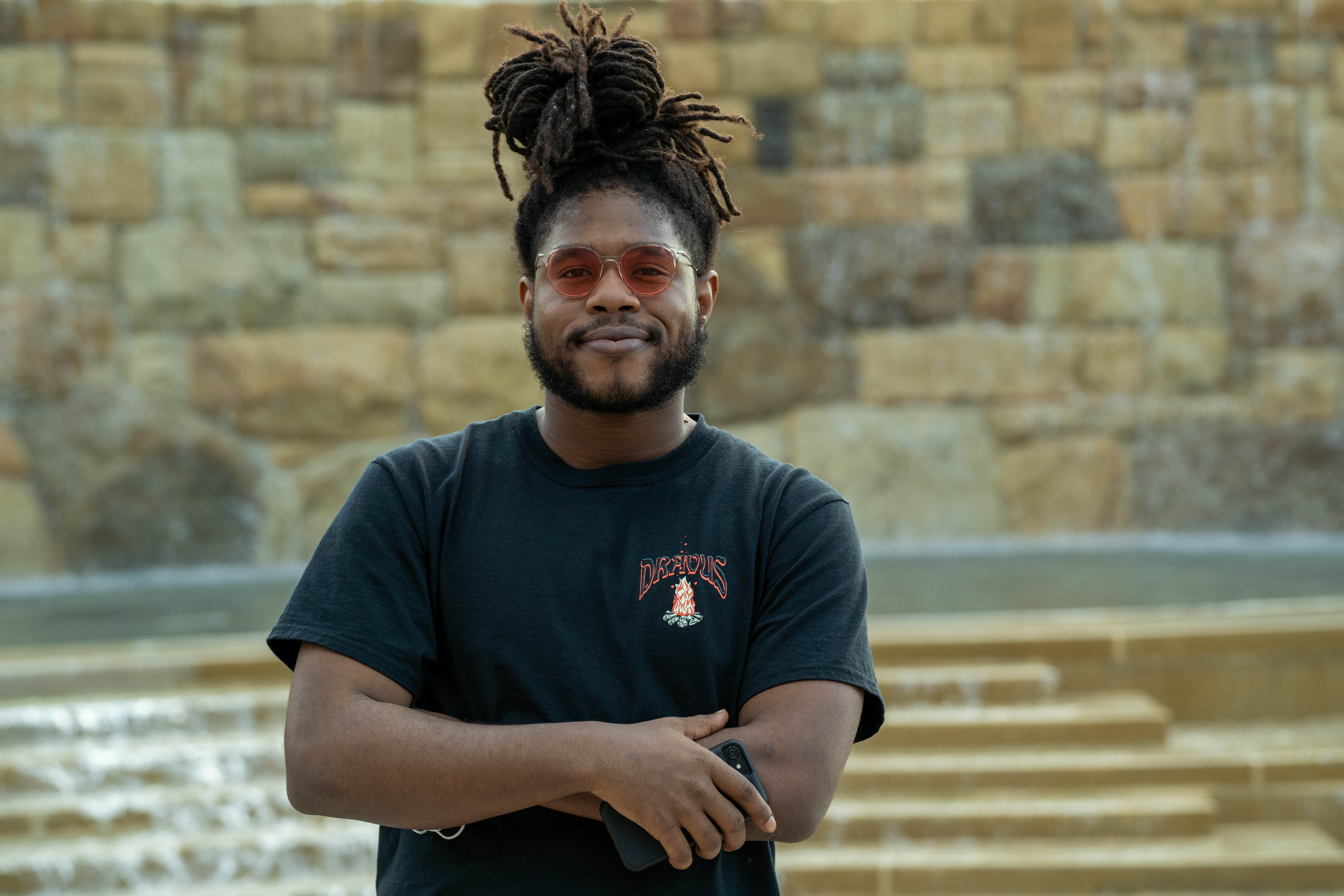 Male transfer student, Jaquan, standing in front of fountain behind Old Main