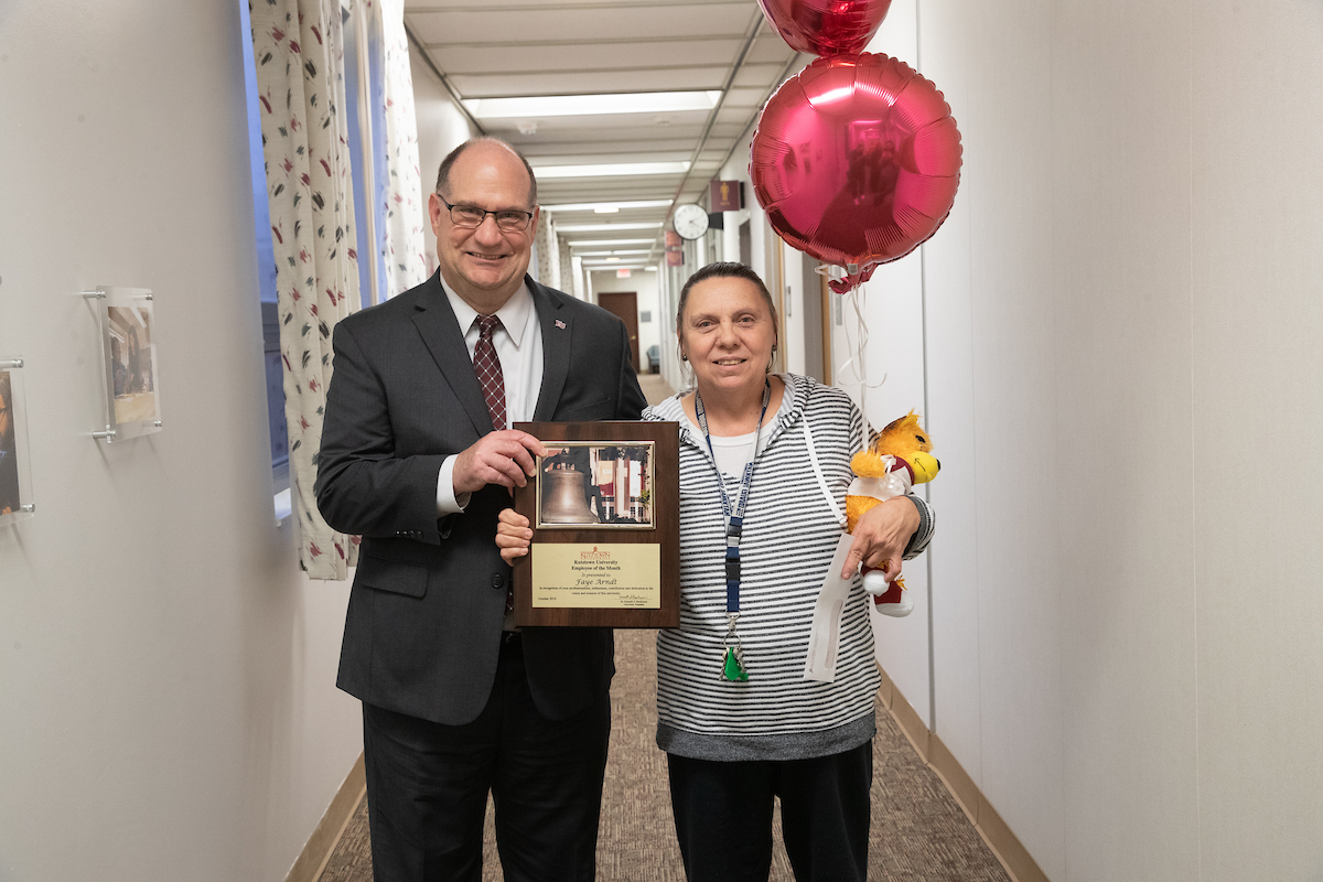 Faye Arndt receiving the Employee of the Month placard, balloons, and stuffed bear from President Hawkinson 