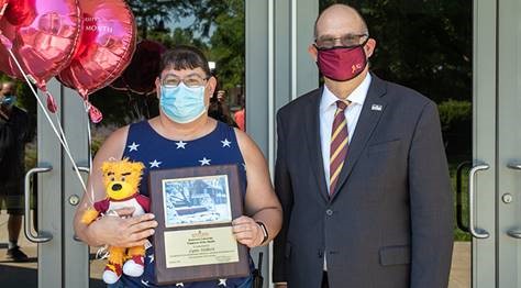 Lynn Hilbert holding her Employee of the Month placard, stuffed bear and balloons next to Dr. Hawkinson 