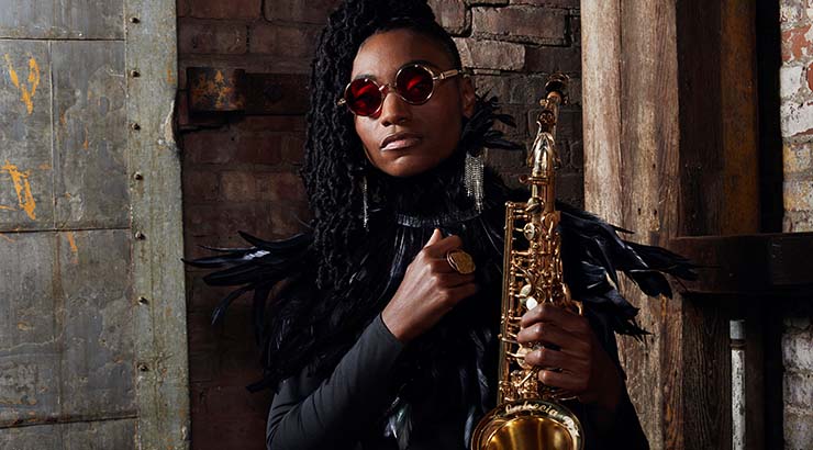 Lakecia Benjamin wearing sunglasses and holding a saxophone