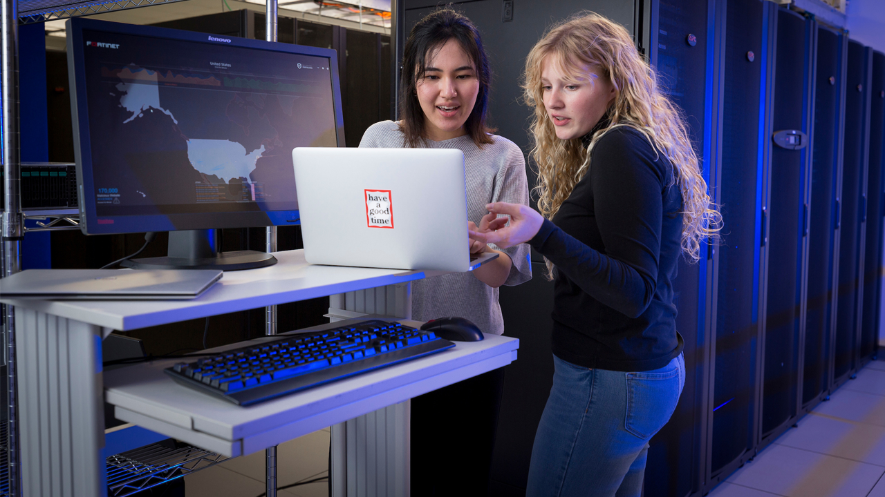 Two students excitedly collaborate over a computer in the Computer Science and Information Technology major.