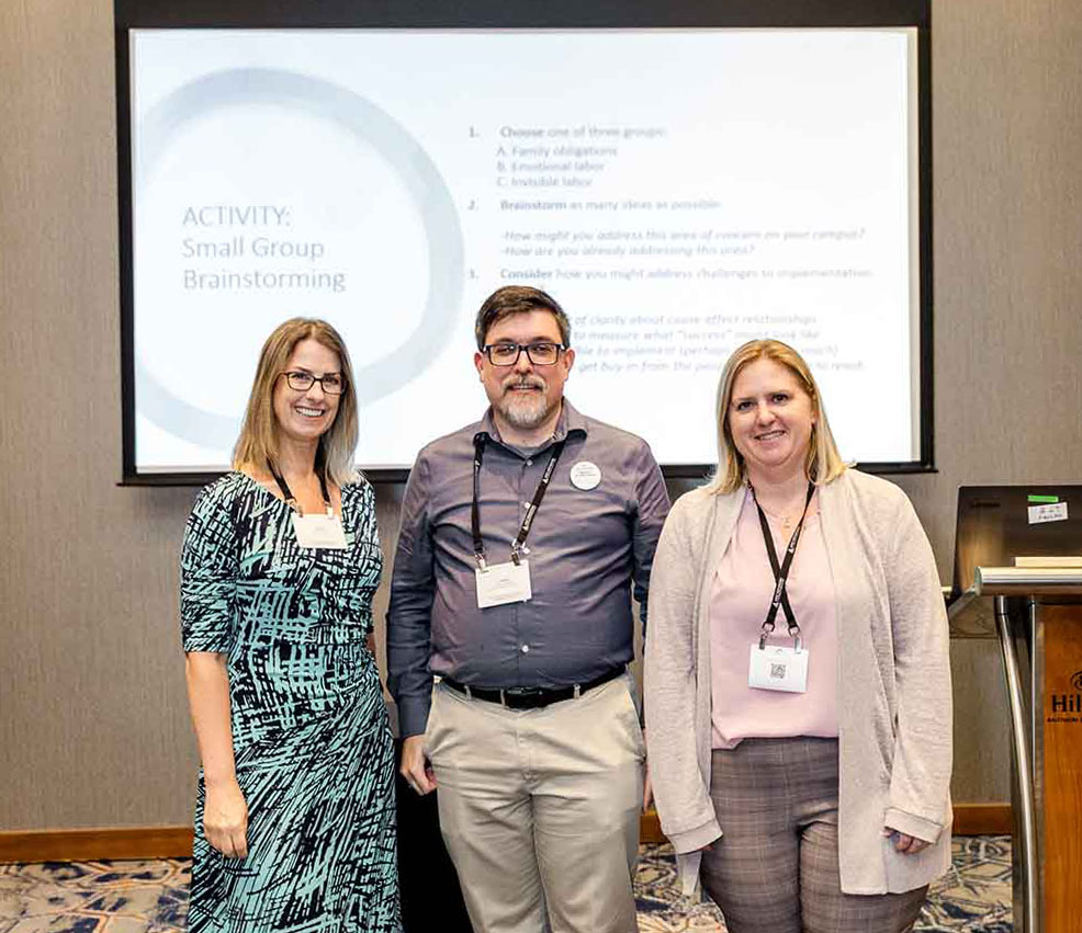 Dr. Laurie McMillan, Dr. Jason Crockett & Dr. Michele Baranczyk (left to right) in front of conference presentation.