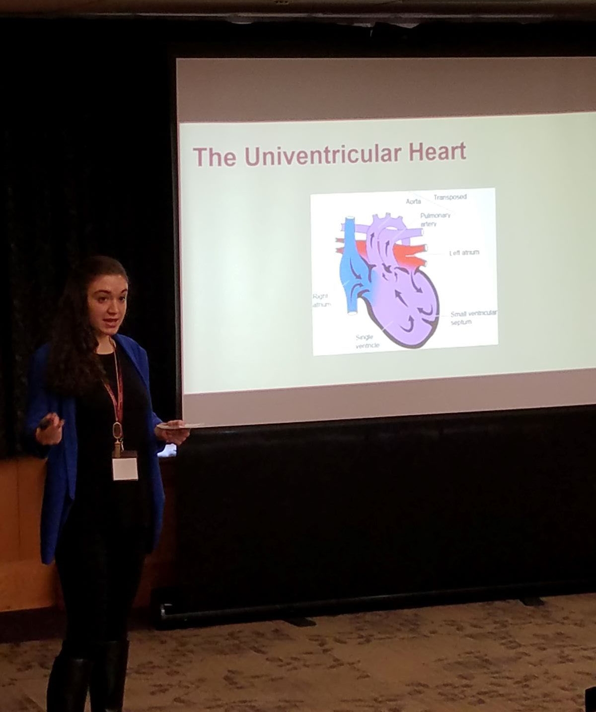 Student presenting at conference with a slide that has a diagram of a univentricular heart