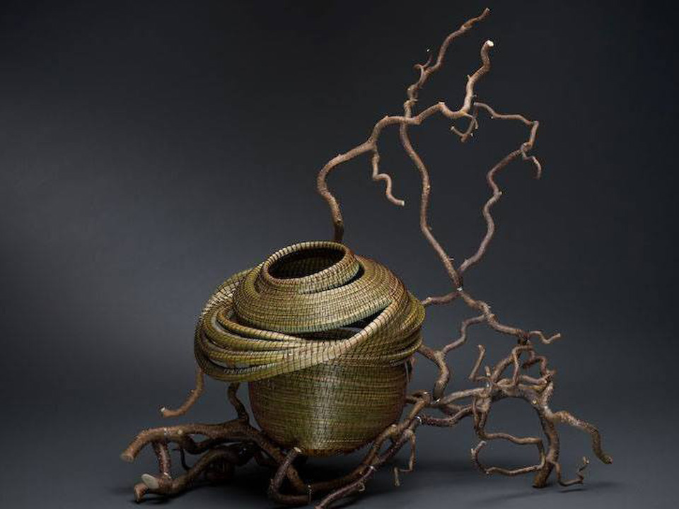 wire sculpture of a broken-down pot next to twisted tree branches 
