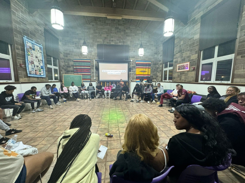 Large group of students sit in a circle at a Black Student Union meeting.