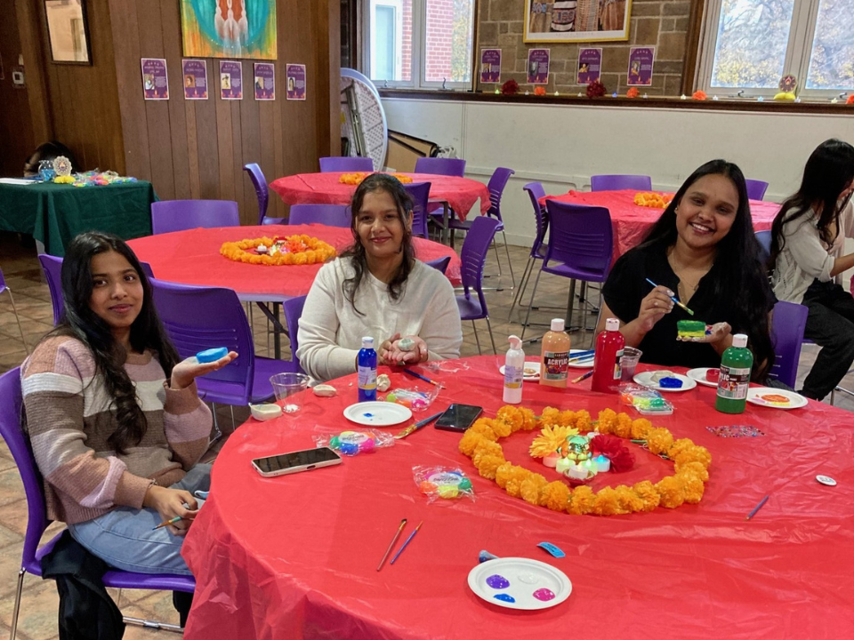 Three students paint clay at a Diwali Celebration in the Multicultural Center.
